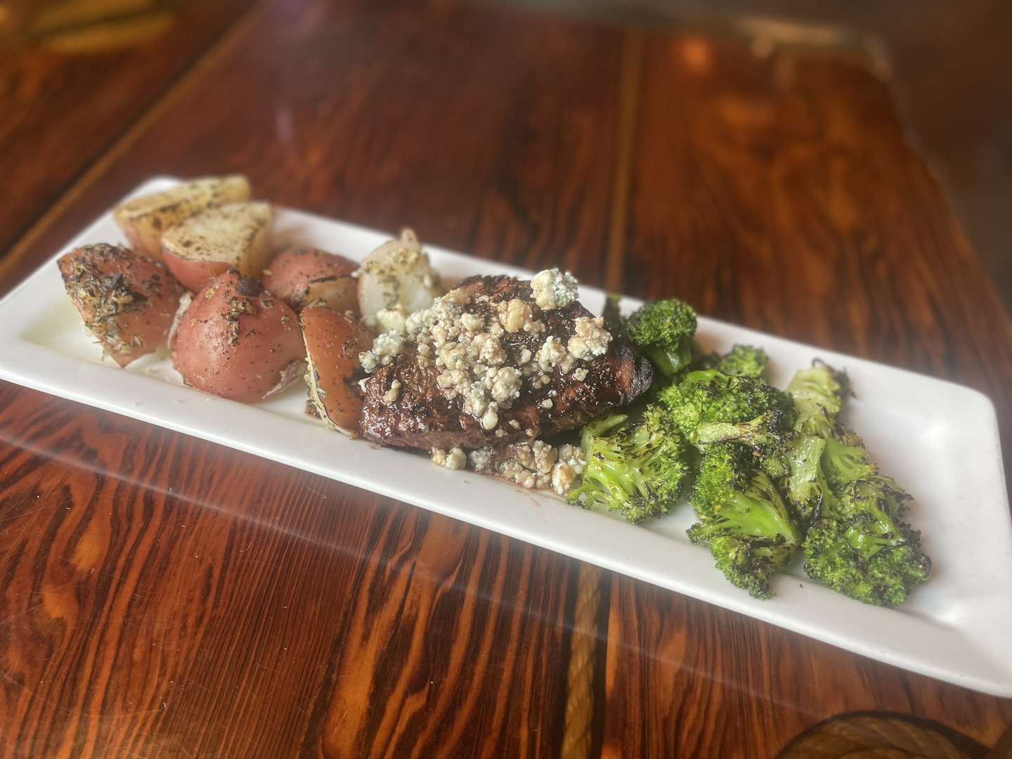 Grilled steak topped with bleu cheese, roasted red potatoes and charred broccoli